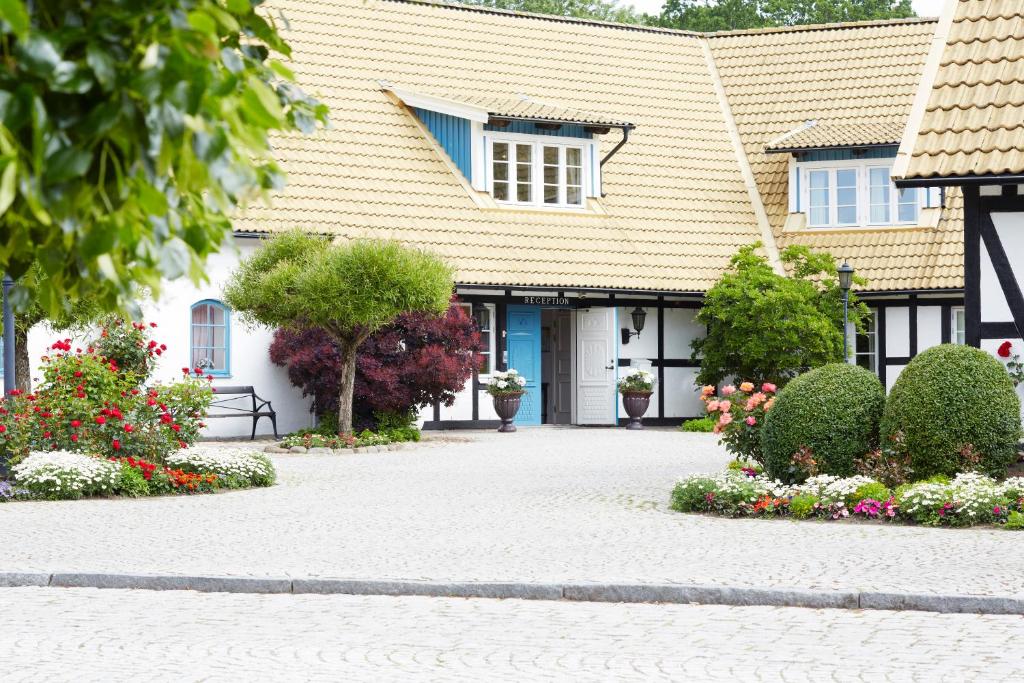 a house with a driveway with flowers in front of it at Margretetorps Gästgifvaregård in Vejbystrand