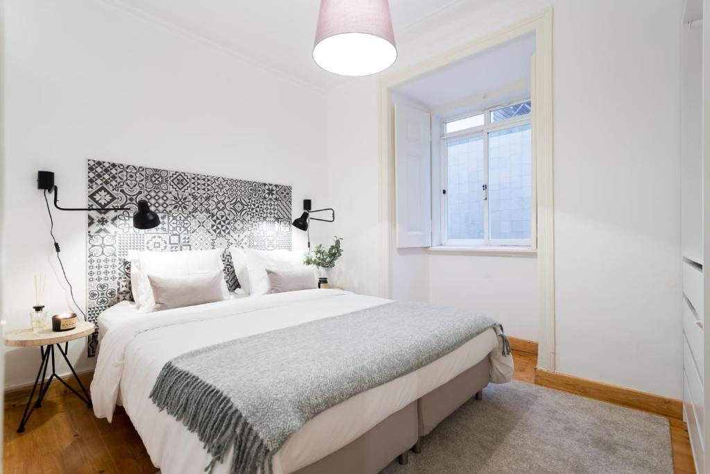 a white bedroom with a large bed and a window at Your Lisbon Home Bairro Alto in Lisbon
