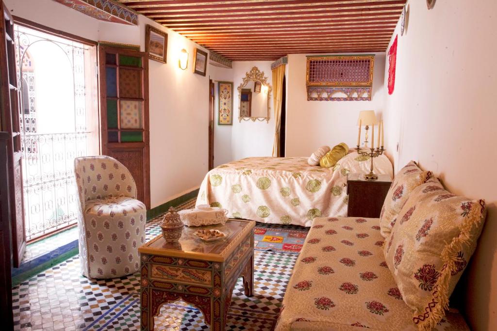 a bedroom with a bed and a couch and a table at Riad Fes Kettani in Fez
