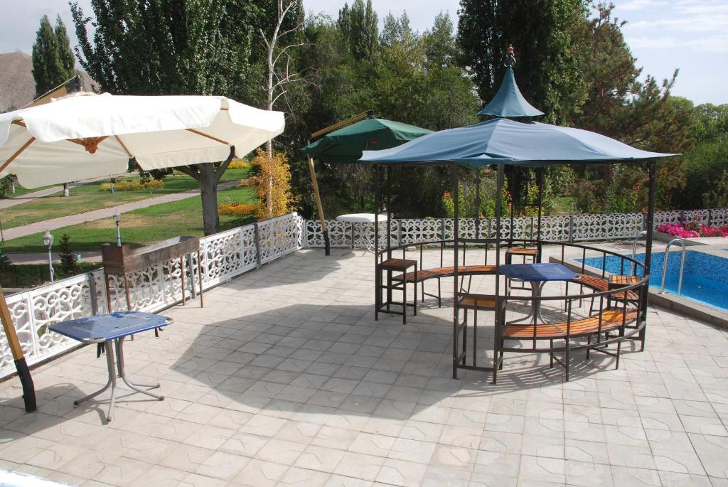a patio with tables and chairs and umbrellas next to a pool at " У Татьяны" in Cholpon-Ata