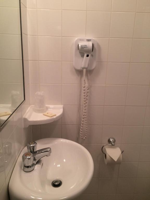 a bathroom with a sink and a phone on the wall at Auberge Centre Ville in Saguenay