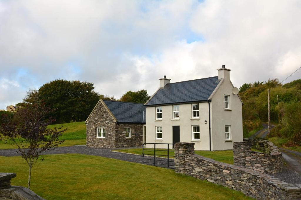 a white house with a stone wall at Rivers Bend Cottage in Skull