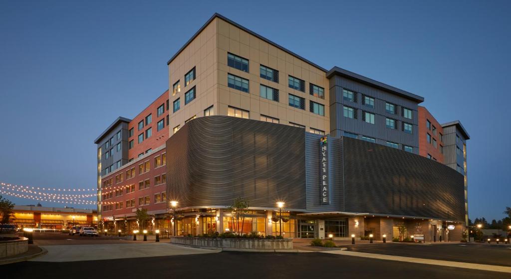 Hyatt Place Eugene/Oakway Center في يوجين: مبنى طويل وبه بناية بها أضواء أمامه