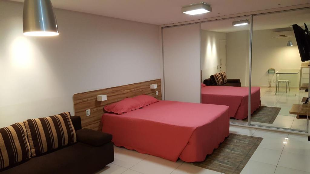 a bedroom with two beds and a couch and a mirror at Apart-Hotel in Goiânia