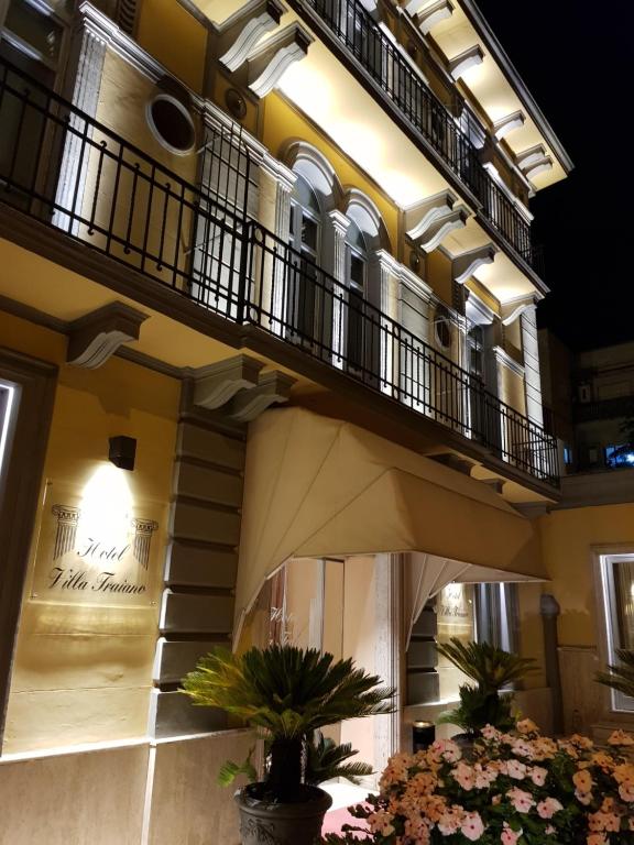 - un bâtiment avec un balcon et des fleurs dans une cour dans l'établissement Hotel Villa Traiano, à Bénévent