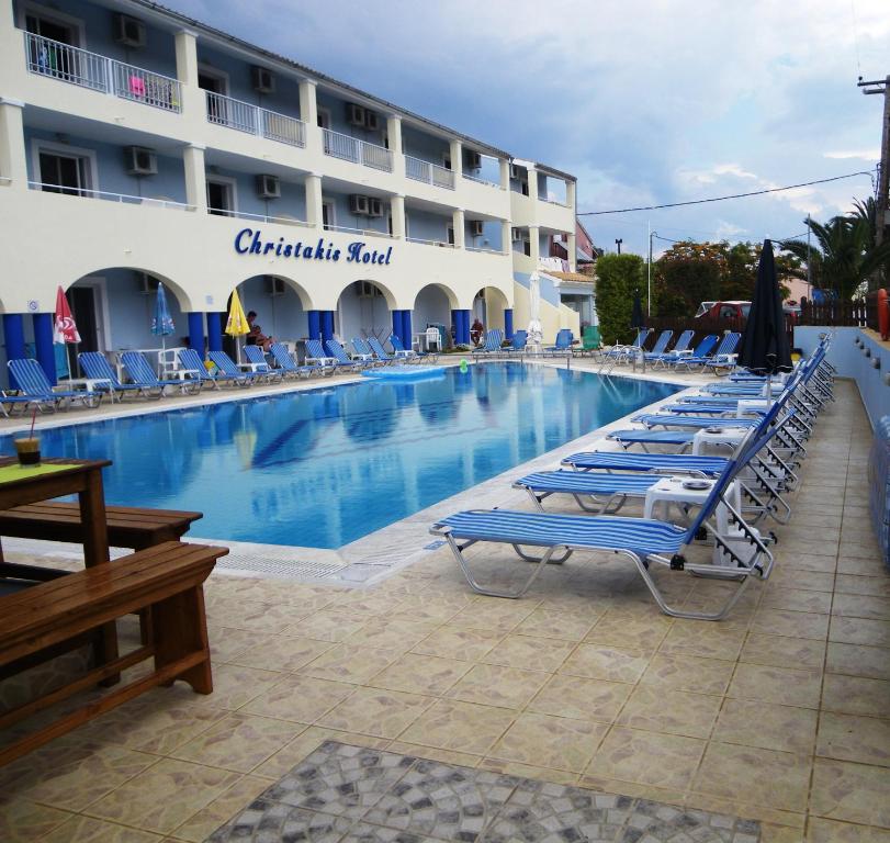 a large swimming pool with lounge chairs and a hotel at Christakis in Sidari