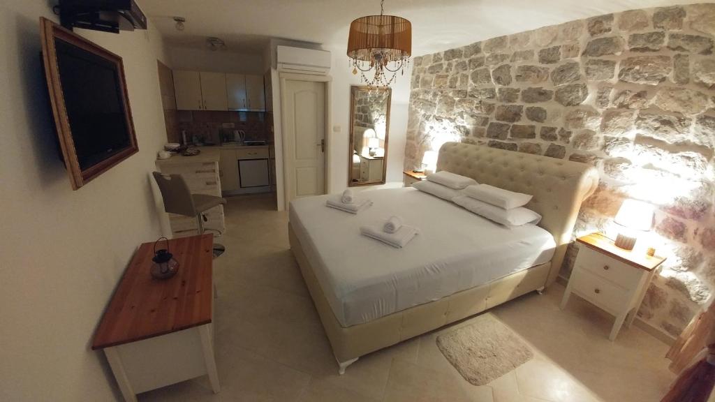a bedroom with a large bed and a stone wall at Bella Vista Zmukic in Perast