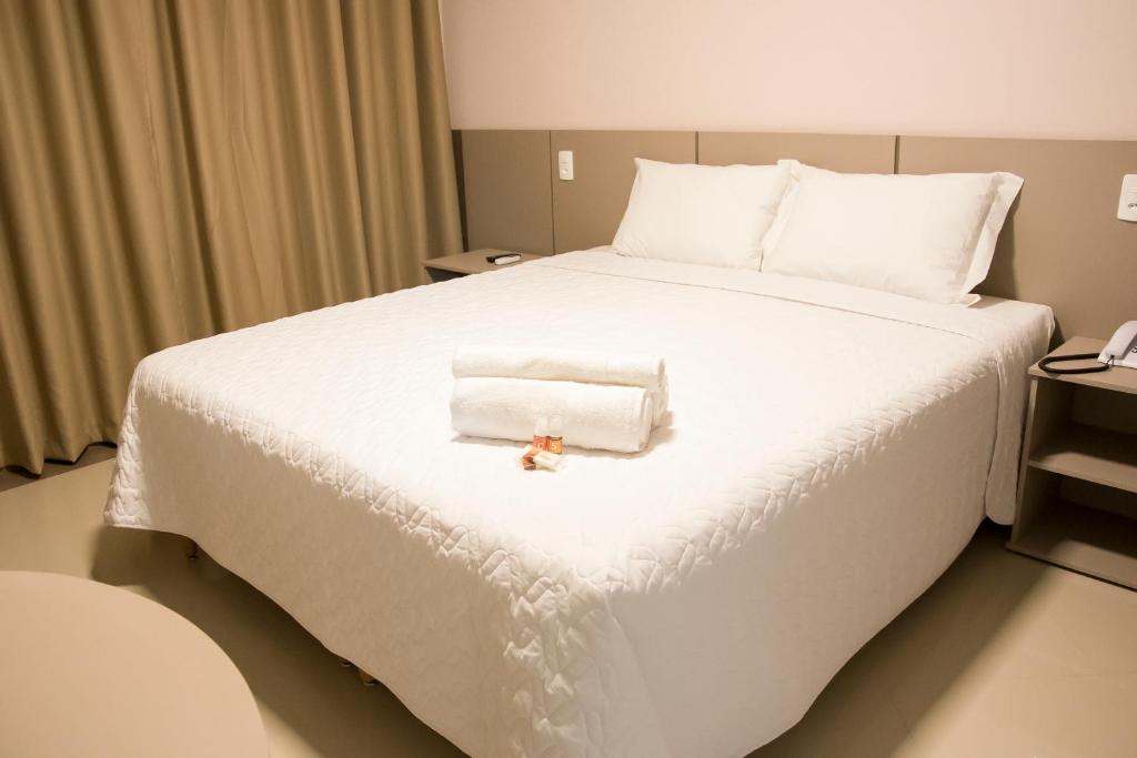 Una cama blanca grande con una toalla. en Paracambi Top Hotel, en Paracambi