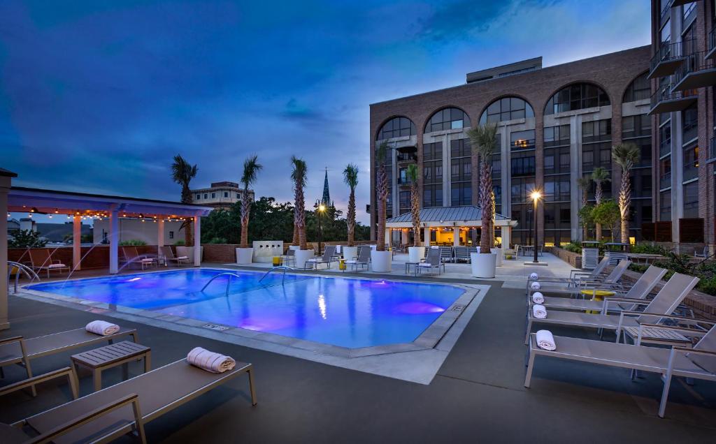 a swimming pool with lounge chairs and a building at The DeSoto in Savannah