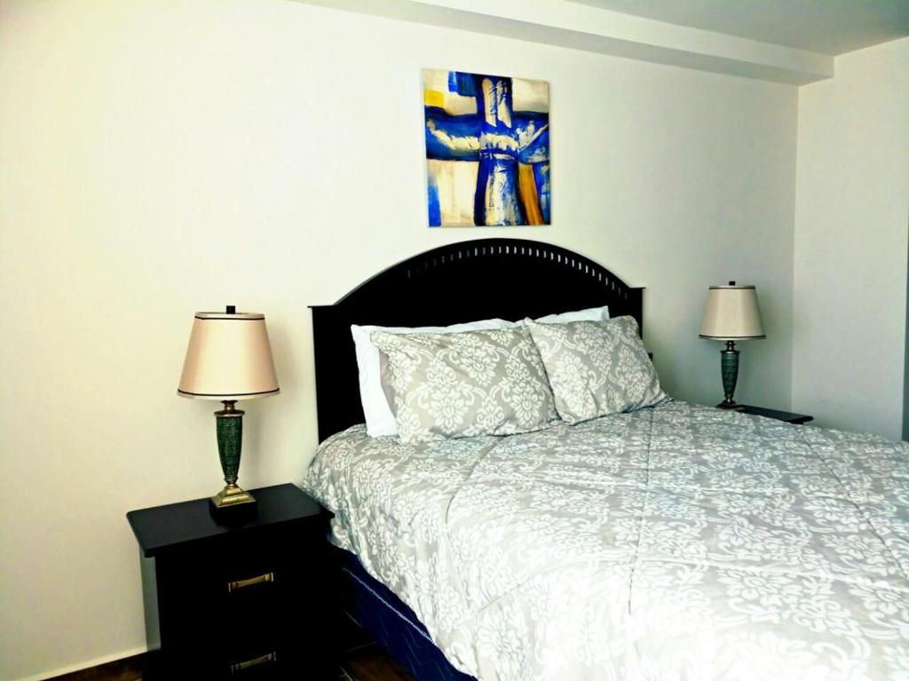 1 dormitorio con 1 cama y 2 mesitas de noche con lámparas en Apartamentos EcoVivienda, en Tegucigalpa