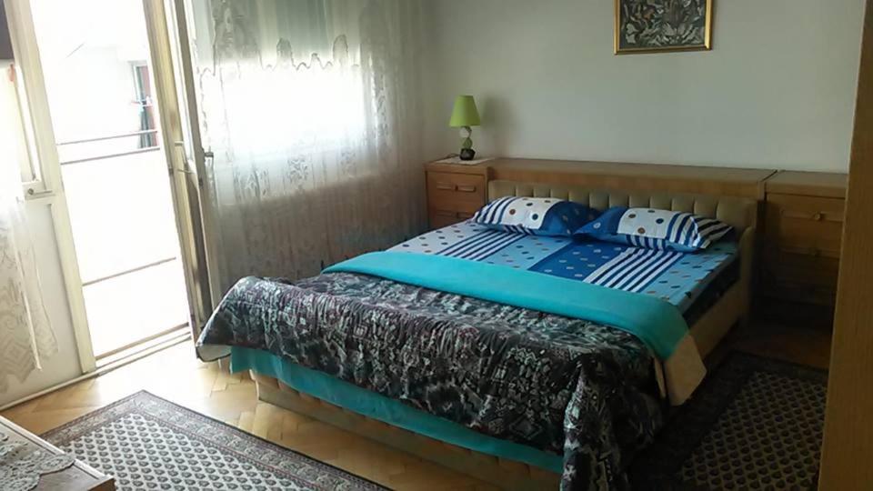a bedroom with a bed with blue sheets and a window at Apartment Centar in Prokuplje
