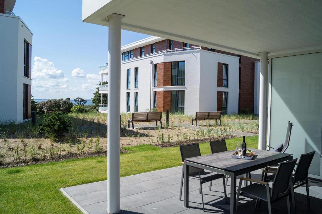 eine Terrasse mit einem Tisch und Stühlen vor einem Gebäude in der Unterkunft Südkap A-02 in Pelzerhaken