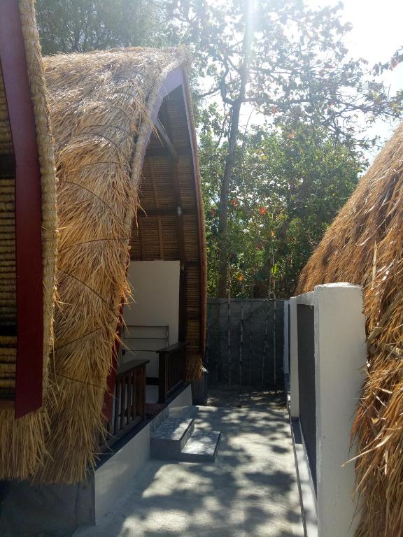 a building with a thatched roof with a pathway at Krisna Bungalows and Restaurant in Sekotong