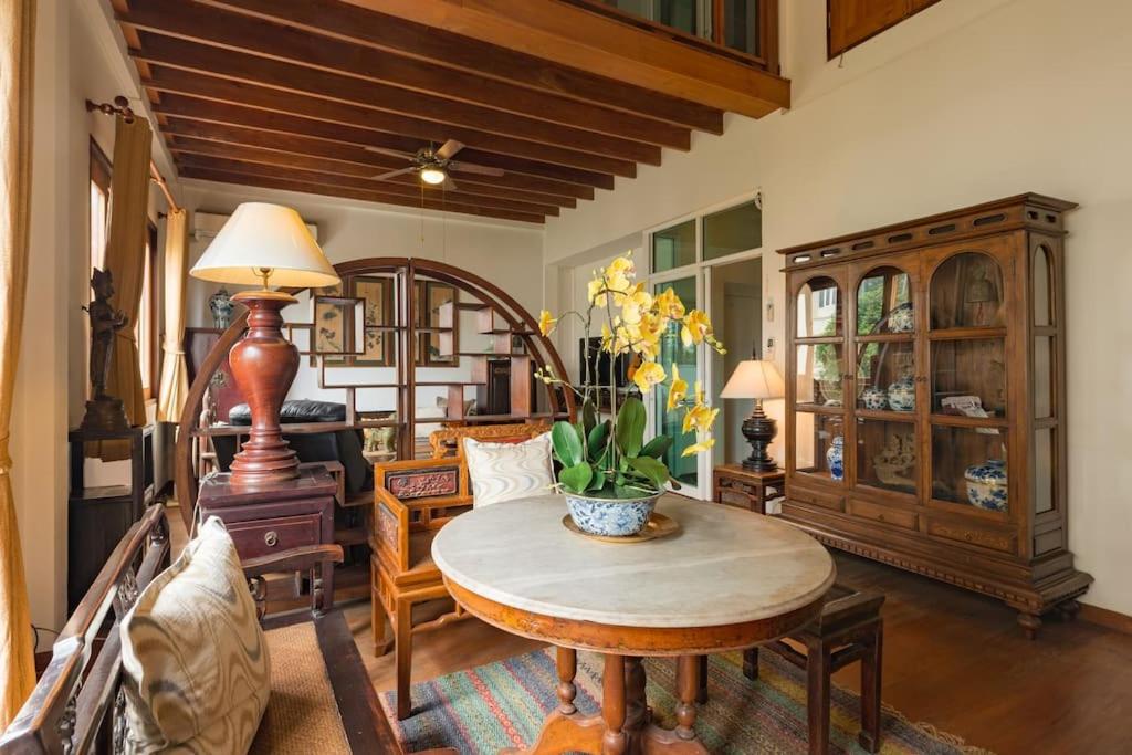 Artisan's Antique House - Silom في بانكوك: غرفة معيشة مع طاولة وبعض الكراسي