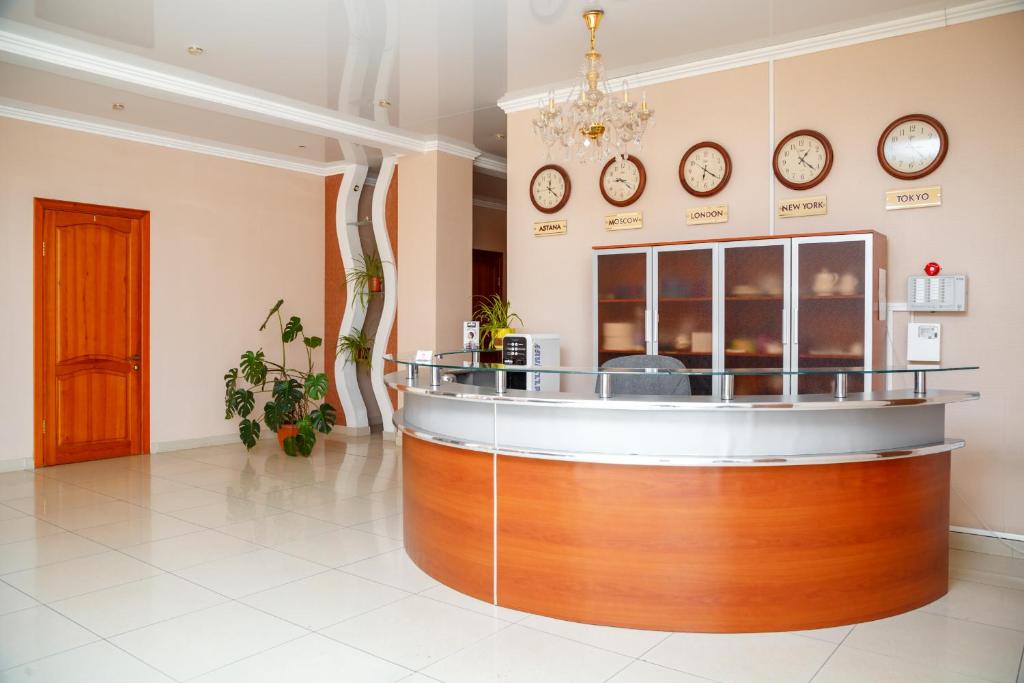 a lobby with a counter with clocks on the wall at Respect Hotel in Pavlodar