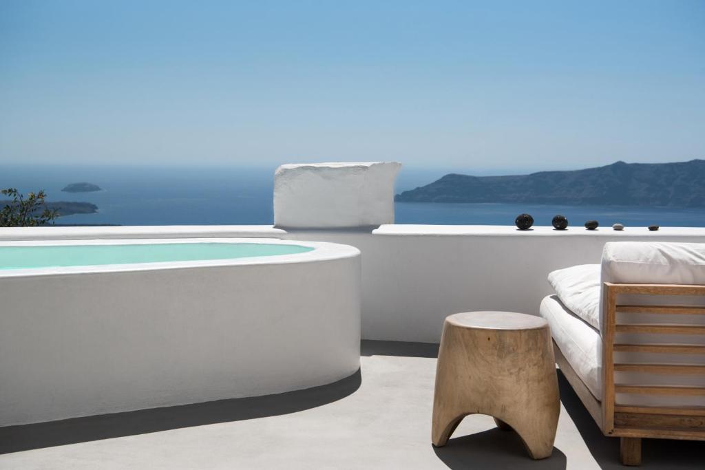 a bathtub and a chair in a room with the ocean at Native Eco Villas in Imerovigli