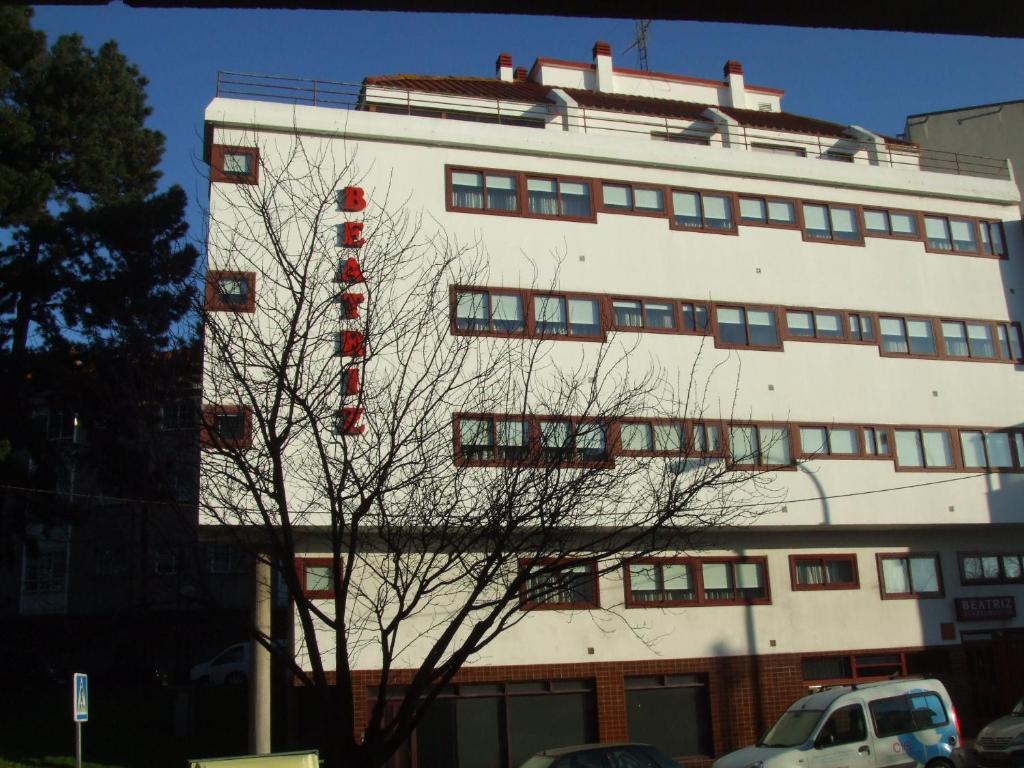 ein hohes weißes Gebäude mit einem roten Schild darauf in der Unterkunft Apartamentos Turisticos Beatriz in Perillo