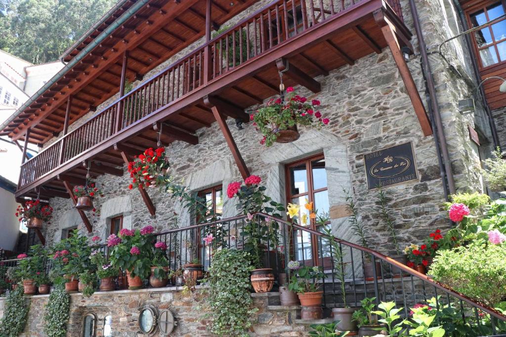 a stone building with potted plants and a balcony at La Casona de Pío in Cudillero