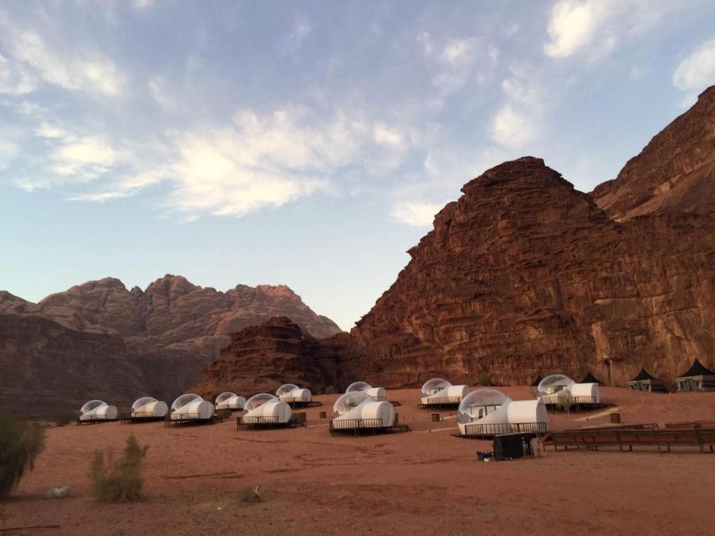 grupa namiotów na pustyni z górami w obiekcie Wadi Rum Night Luxury Camp w mieście Wadi Rum