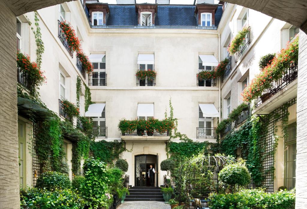 Une allée en face d'un bâtiment avec des plantes dans l'établissement Relais Christine, à Paris