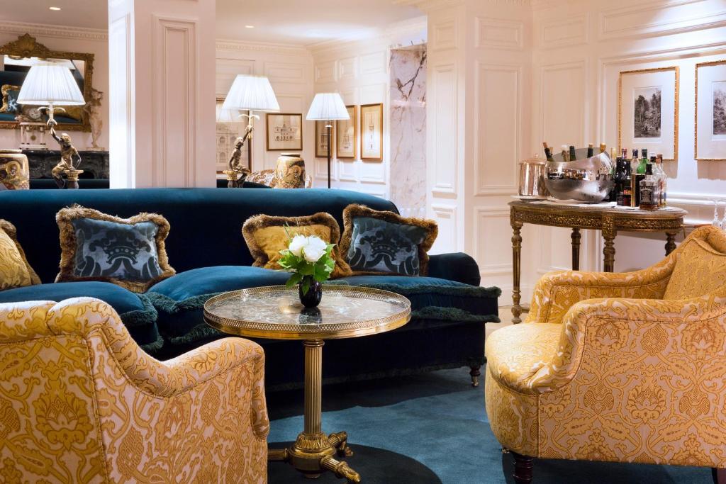 a living room with blue couches and a table and chairs at Relais Christine in Paris