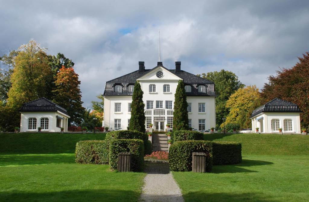 a large white house with a pathway in front of it at Baldersnäs Herrgård in Dals Långed