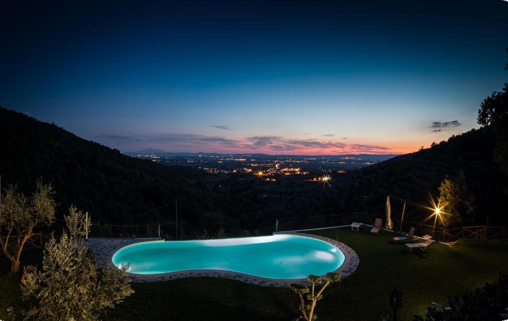 una piscina nel mezzo di un cortile di notte di Il Castello di Rigutinelli ad Arezzo
