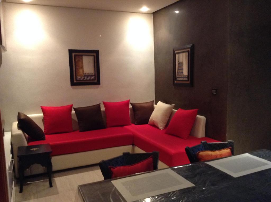 Appartement Rabat Haut Agdal في الرباط: غرفة معيشة مع أريكة حمراء مع وسائد حمراء