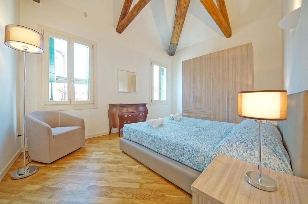 a bedroom with a bed and a chair and two lamps at DolceVita Apartments N 394 in Venice