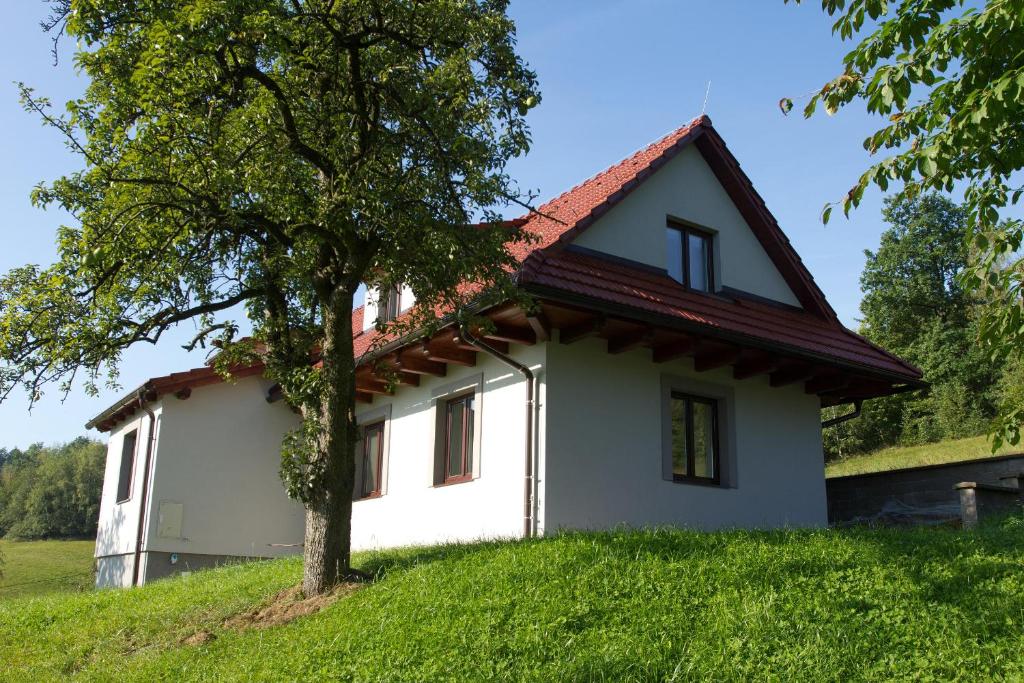 a small white house on a hill with a tree at Chalupa pod Hruškou in Zubří
