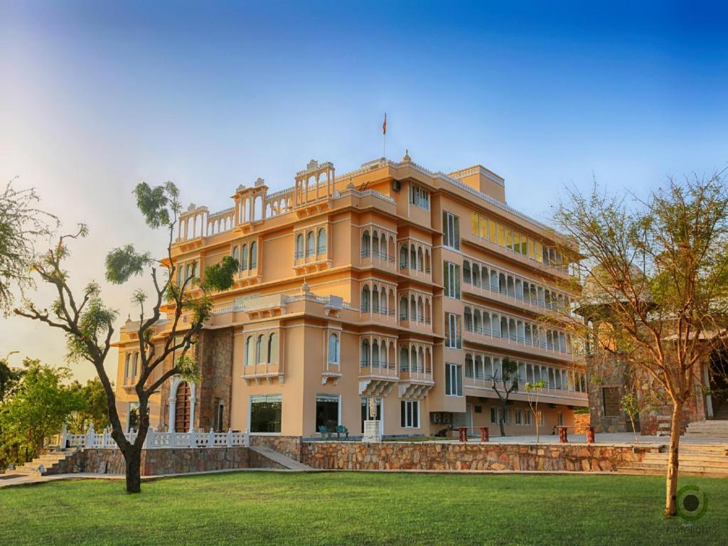a large yellow building with a grassy field in front of it at Fateh Niwas by Fateh Collection in Udaipur