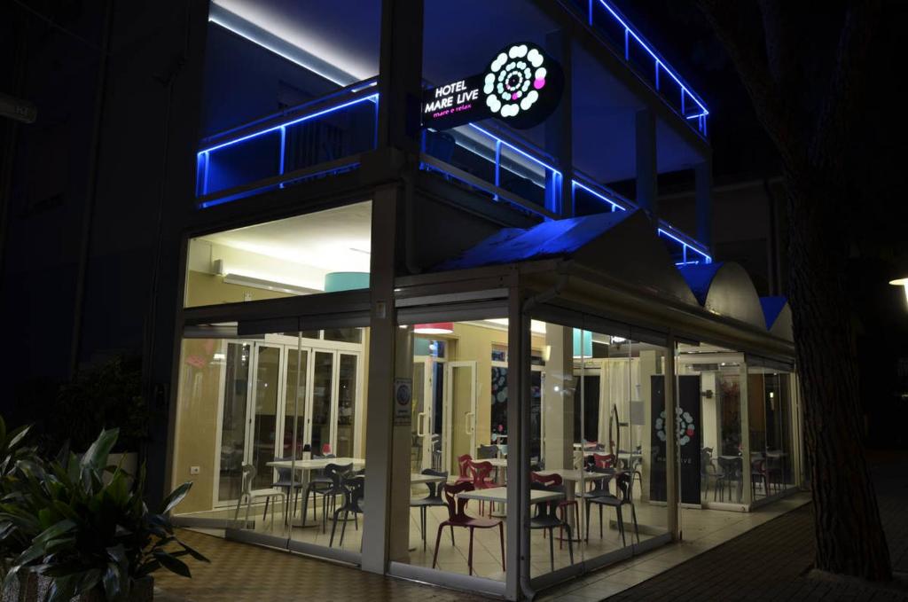 リド・ディ・イエゾロにあるHotel Mare Liveの夜はテーブルと椅子のあるレストランを利用できます。