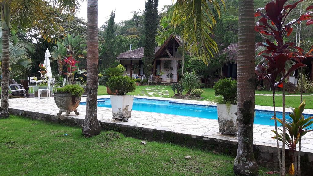 a swimming pool in a yard with palm trees at Chacara de Cinema da Montanha in Itariri