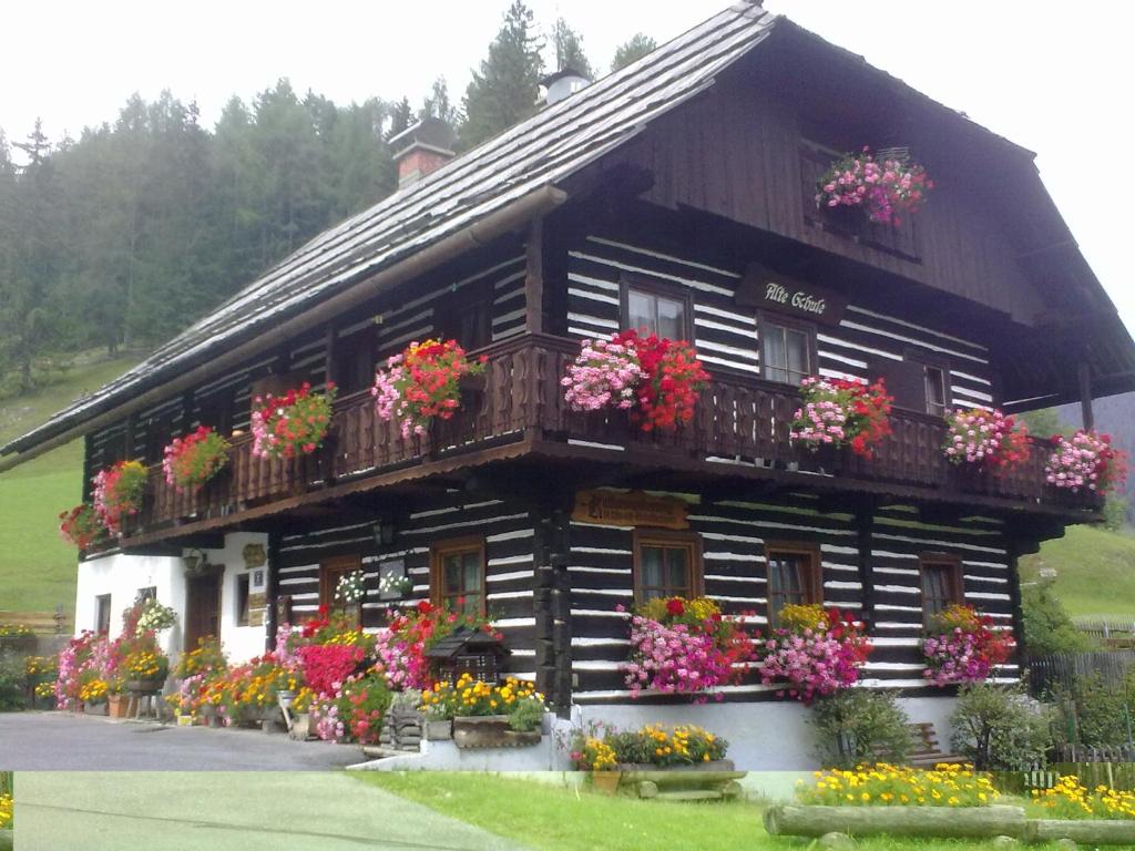 ein Holzhaus mit Blumen auf dem Balkon in der Unterkunft Alte Schule in Bad Kleinkirchheim