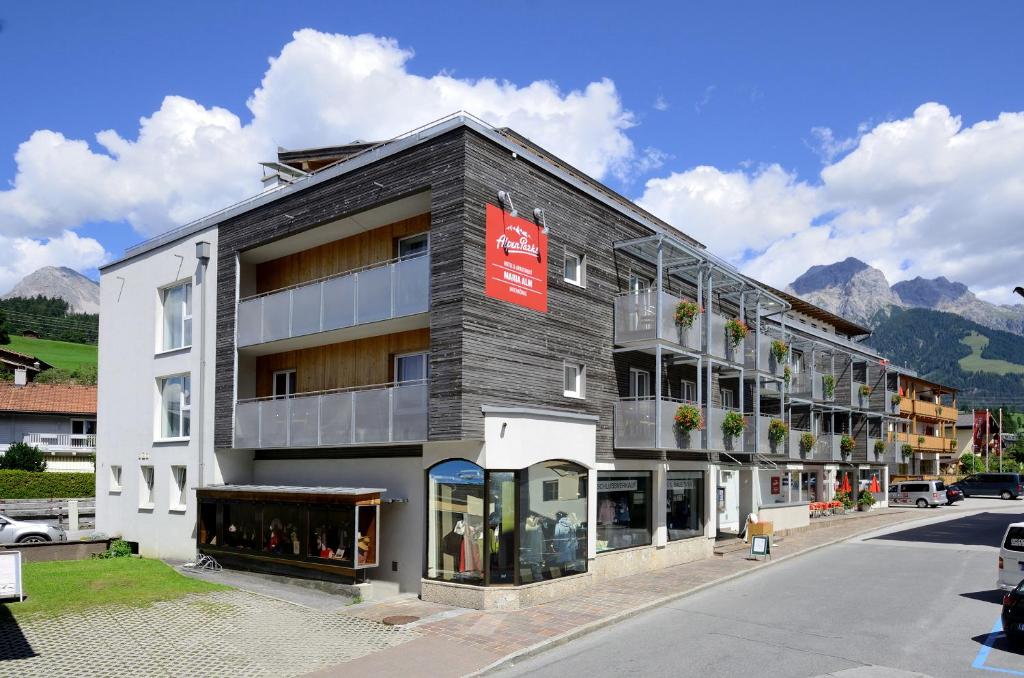 un edificio en una calle con montañas en el fondo en AlpenParks Hotel Maria Alm en Maria Alm am Steinernen Meer