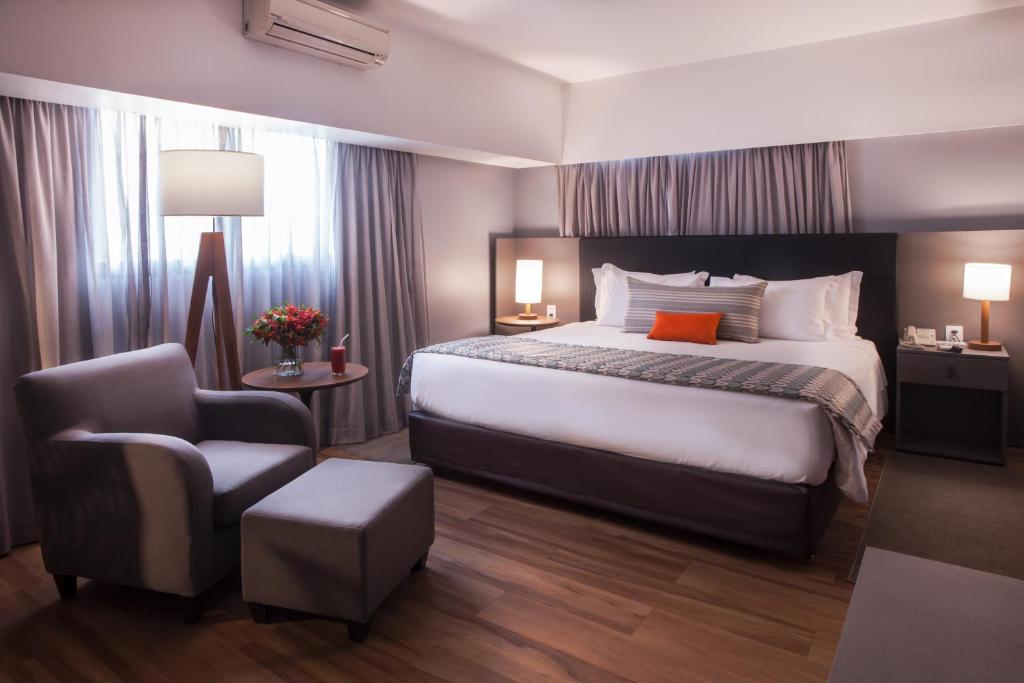 a hotel room with a bed and a chair at Wyndham São Paulo Berrini in São Paulo