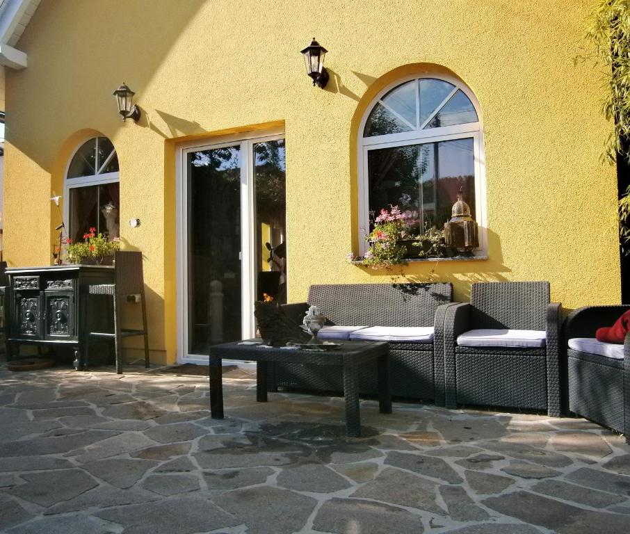un bâtiment jaune avec des chaises et une table sur une terrasse dans l'établissement Haus Daniela, à Klagenfurt am Wörthersee