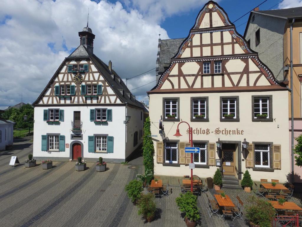 two buildings with tables and chairs in a town at Hotel zur Schloß-Schenke in Neuwied