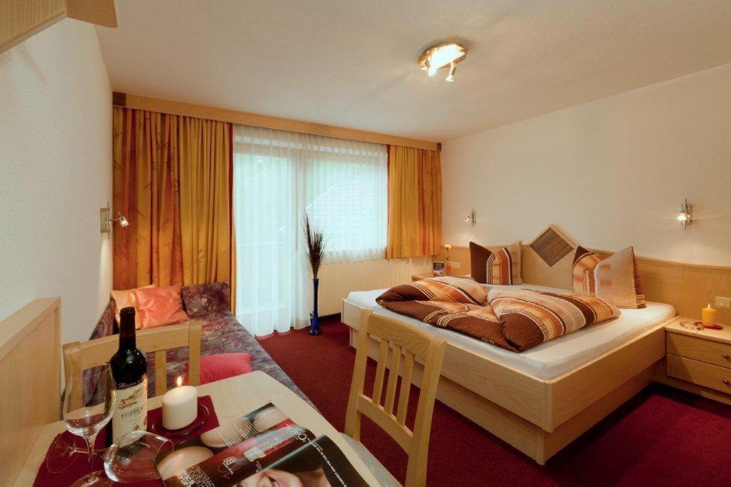 ein Hotelzimmer mit einem Schlafzimmer mit einem Bett und einem Tisch in der Unterkunft Haus Birgit in Pettneu am Arlberg