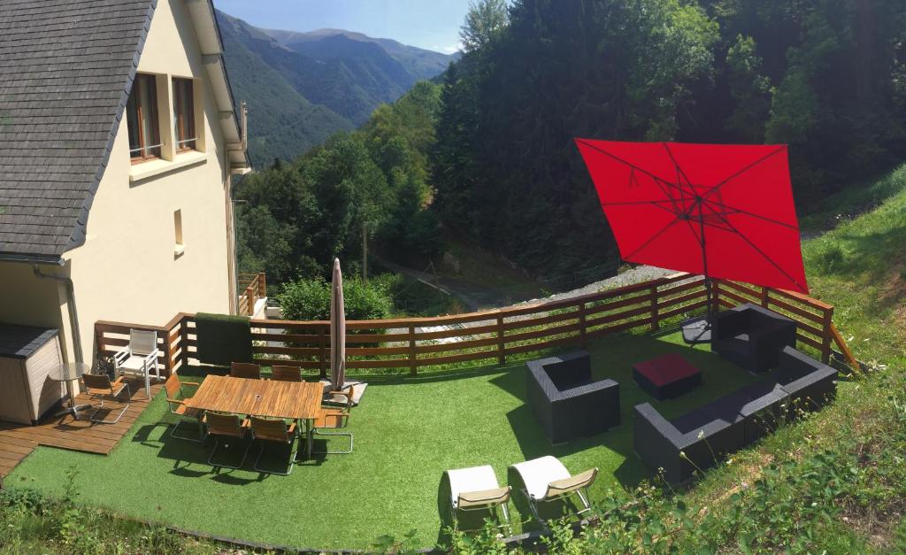 a patio with a table and chairs and a red umbrella at La Maison D'ILHAN in Ilhan