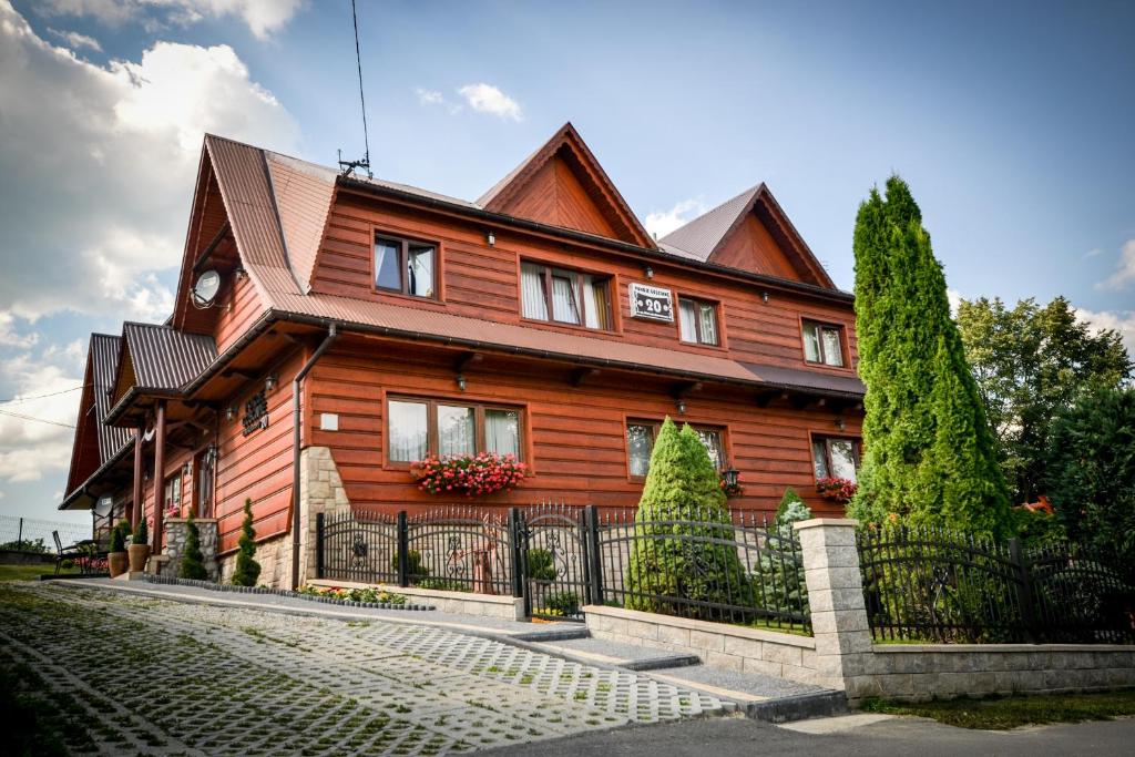 una casa de madera con una valla delante en Pokoje Gościnne Helena, en Bukowina Tatrzańska