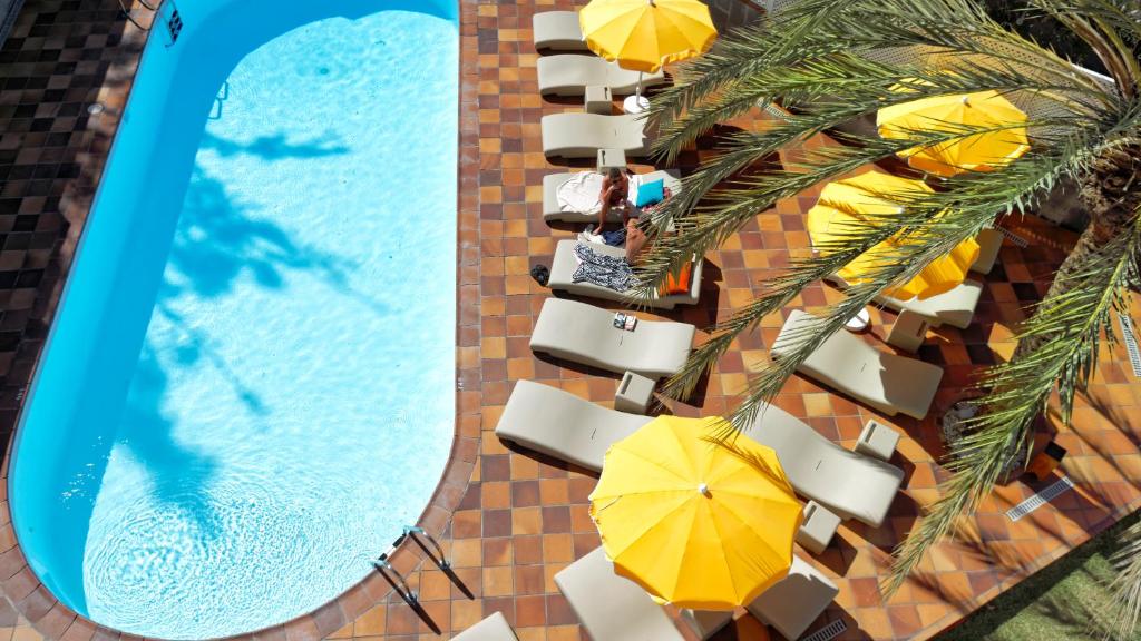 uma vista superior para uma piscina com cadeiras e guarda-sóis em Jacarandas Beach em Playa del Inglés