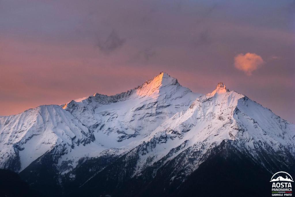 a snow covered mountain with a sunset in the background at Appartamento Pommier in Saint-Pierre