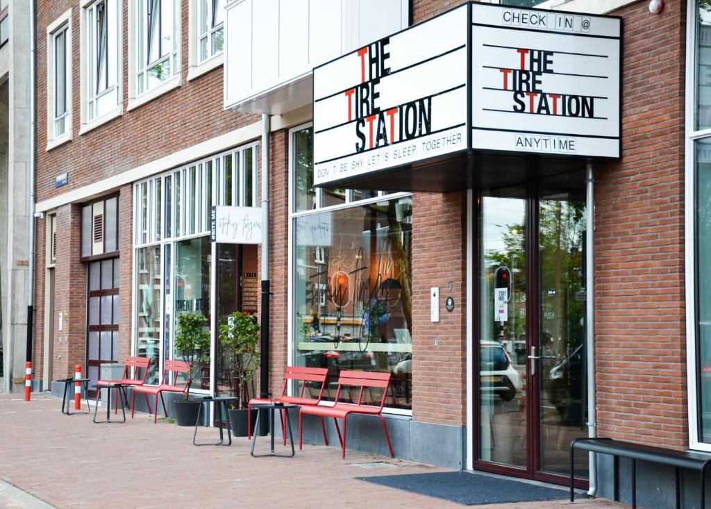 a store front with red tables and chairs on a street at Conscious Hotel The Tire Station in Amsterdam