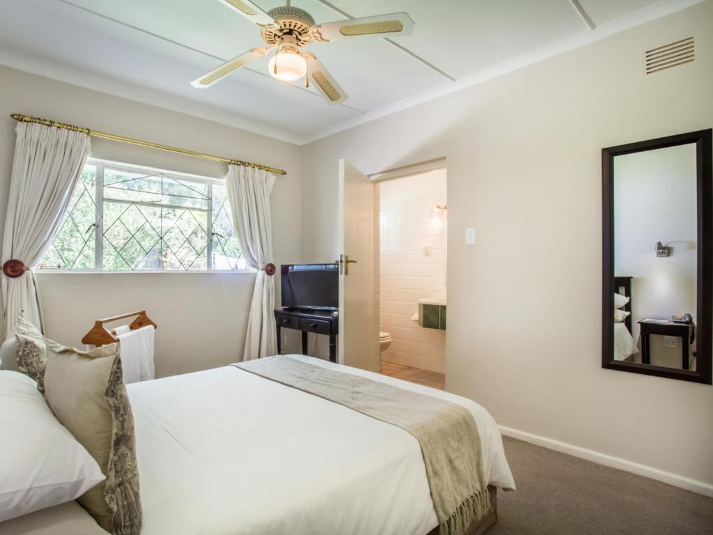 a bedroom with a bed and a ceiling fan at Hlangana Lodge in Oudtshoorn