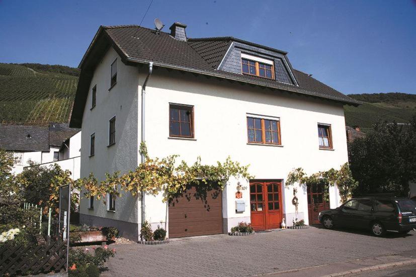 a white house with a red door and a car at Weingut Berweiler in Klüsserath