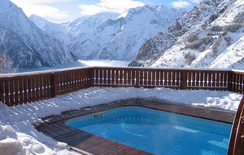 uma piscina na neve com vista para as montanhas em Odalys Chalet Le Ponton em Les Deux Alpes