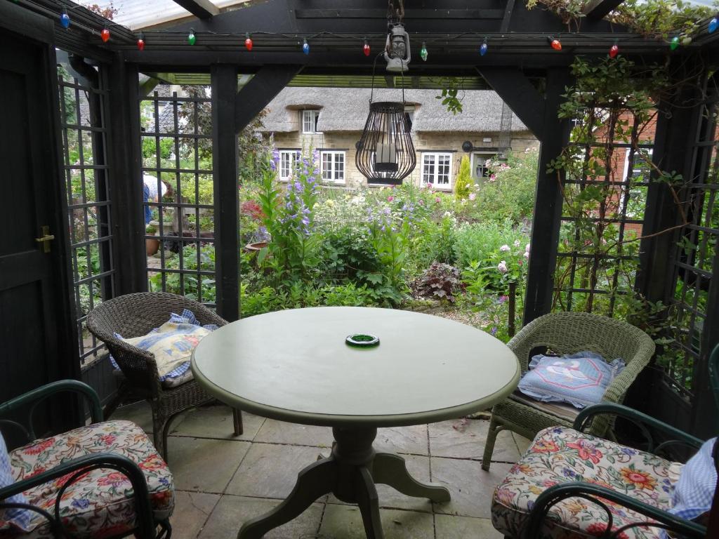a table and chairs on a patio with a garden at Moat Cottage Barns in Corby