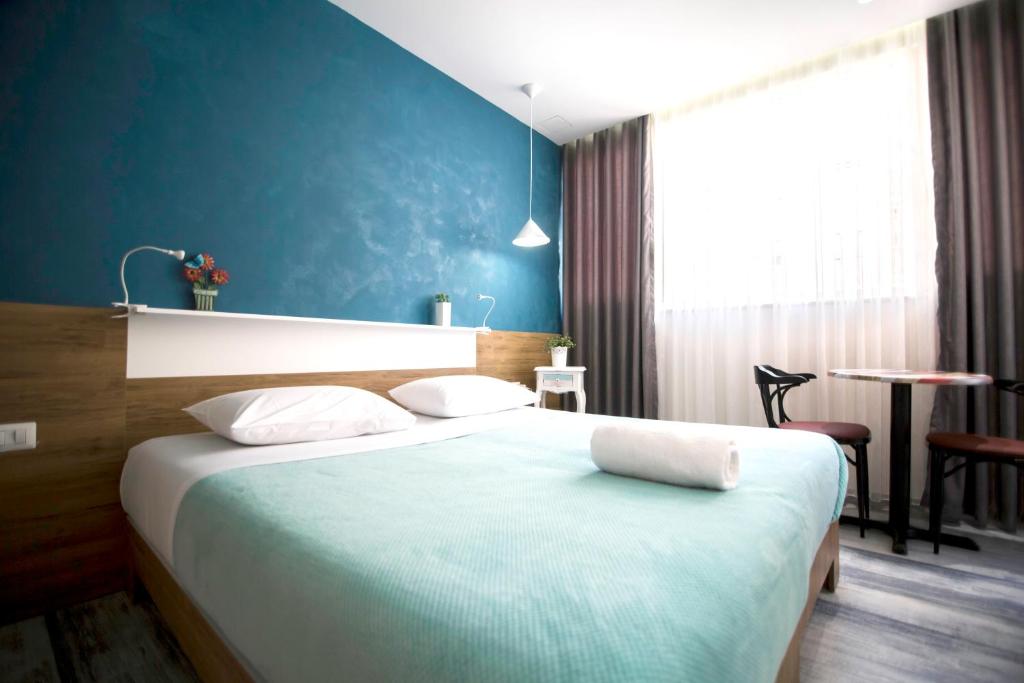 sypialnia z dużym łóżkiem z niebieską ścianą w obiekcie Urban Rooms w Tiranie