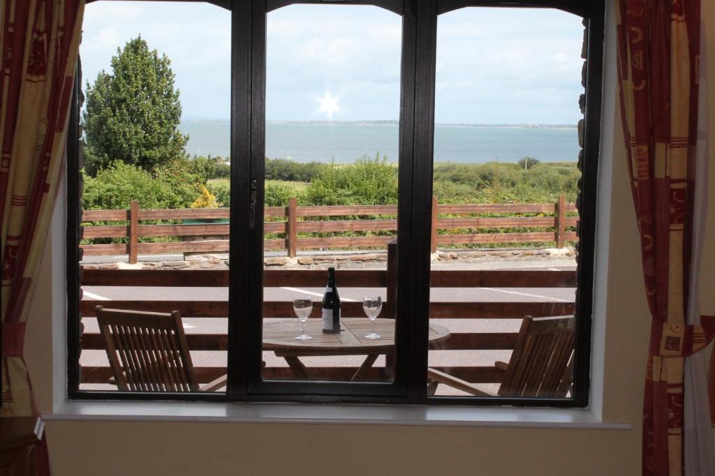 a window with a table with a bottle of wine at Tralee Bay Holiday Village in Castlegregory